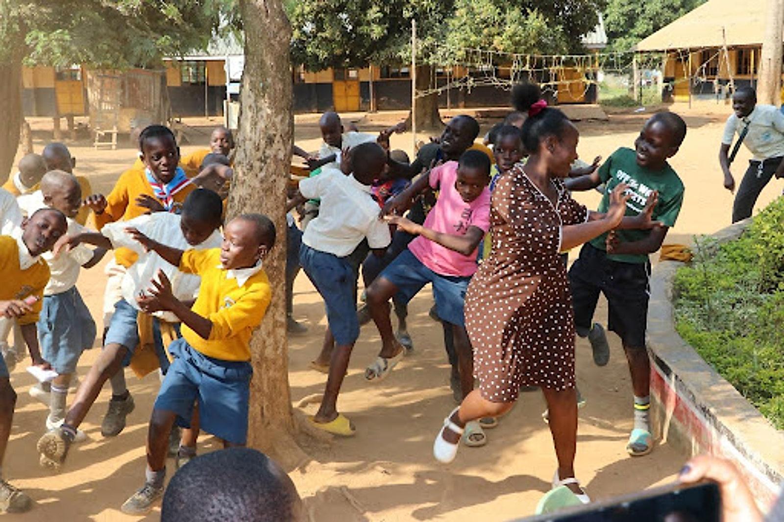 A mentor leading schoolchildren in a lively outdoor activity in a school yard